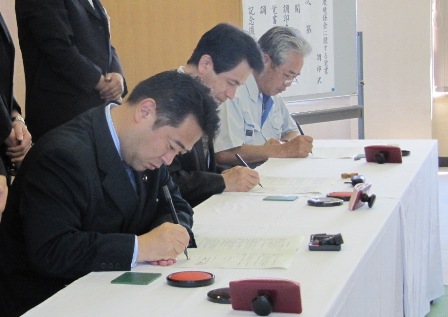 佐久市長、佐久総合病院長、佐久市中央工業会三者による調印式での署名の様子。