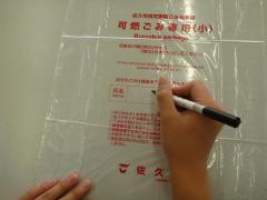 ごみ指定袋へ氏名を記名する様子の画像