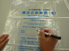 埋立ごみ指定袋へ氏名を記入している様子の画像