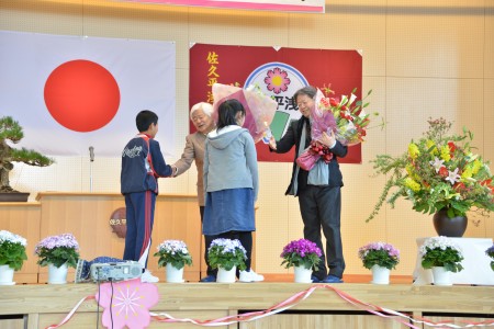 山川啓介さん、タケカワユキヒデさんに花束を贈呈する様子の画像