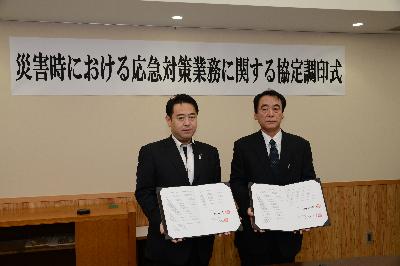 測量設計業連絡協議会の方と協定書を掲げる市長の画像