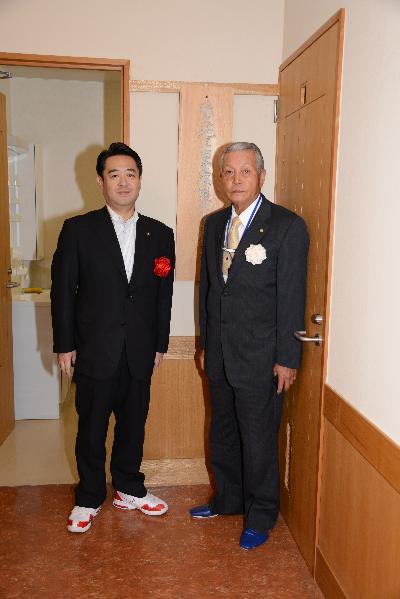 センターの入口に立つ保護士会の岡本会長と市長の画像