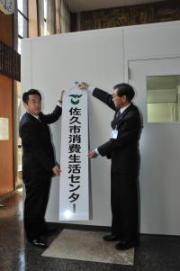 消費生活センターの看板を掲げる市長と環境部長の画像