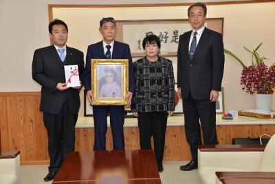 大工原様の遺影をもったご親族と並びに市長、教育長の画像